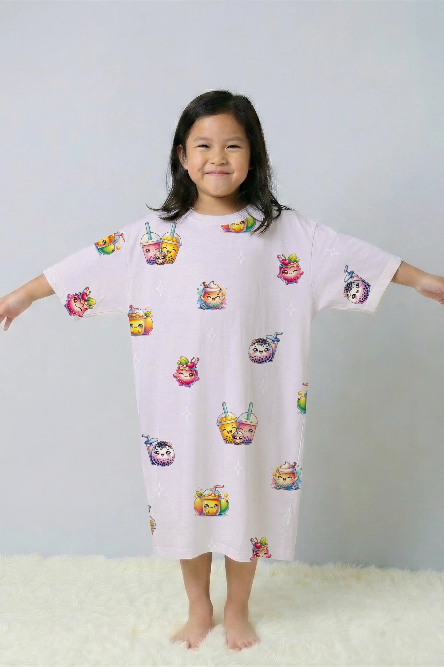 Child model with arms outstretched showing the loose, comfortable fit of the girls' oversized bamboo sleep tee. Featuring a kawaii bubble tea and boba design, this is the perfect matching sleepwear for families.