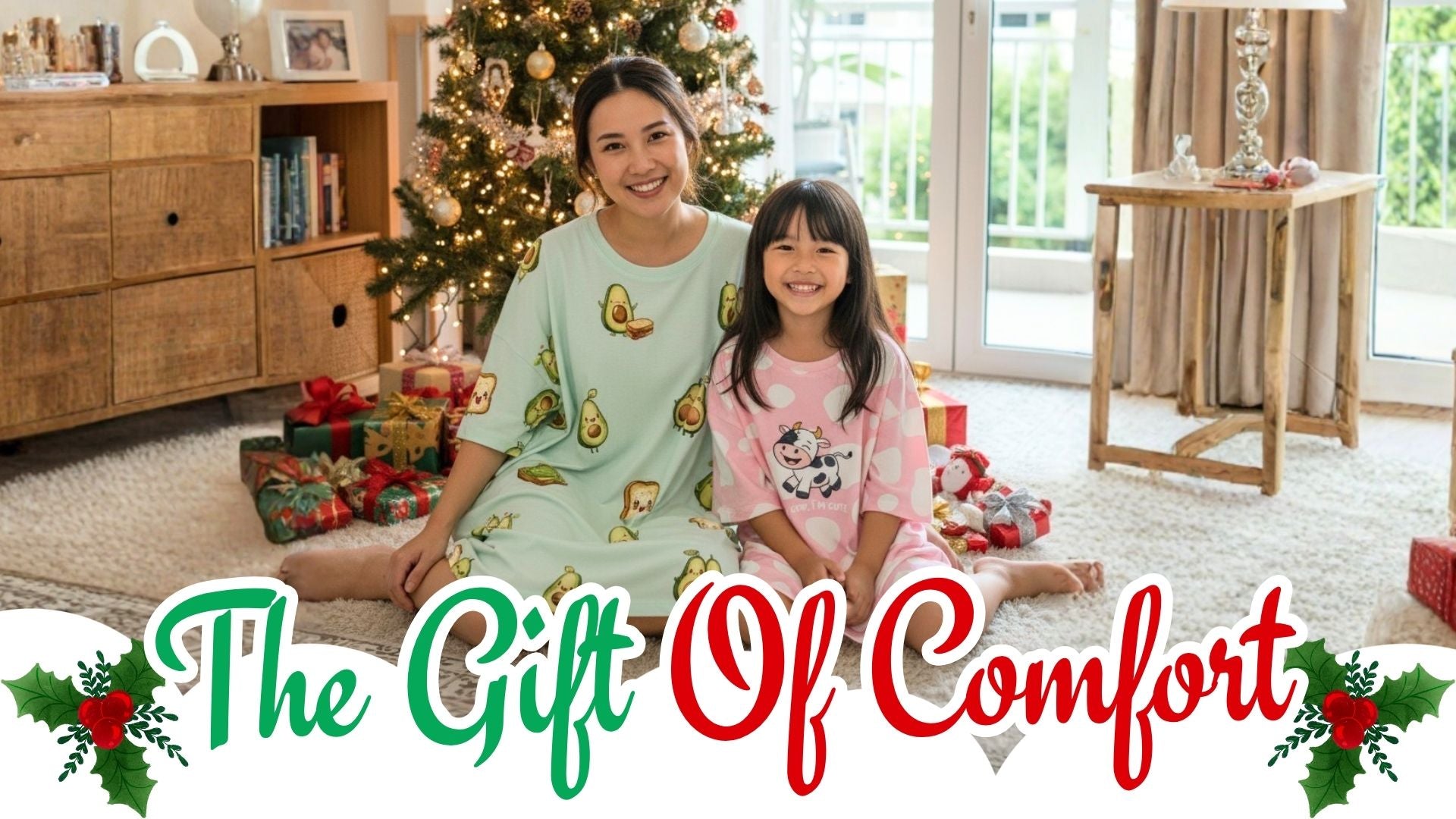 Woman and child in pajamas sitting on the floor in a cozy living room with Christmas decorations.